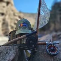 Rise Beyond fly rod siting next to a Rep your Waters hate and fly fishing bag on Clear Creek in colorado