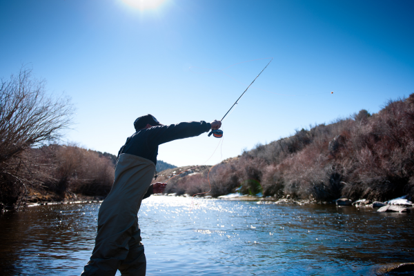 Angler fly fishing in a snow-fed river during spring runoff in Colorado