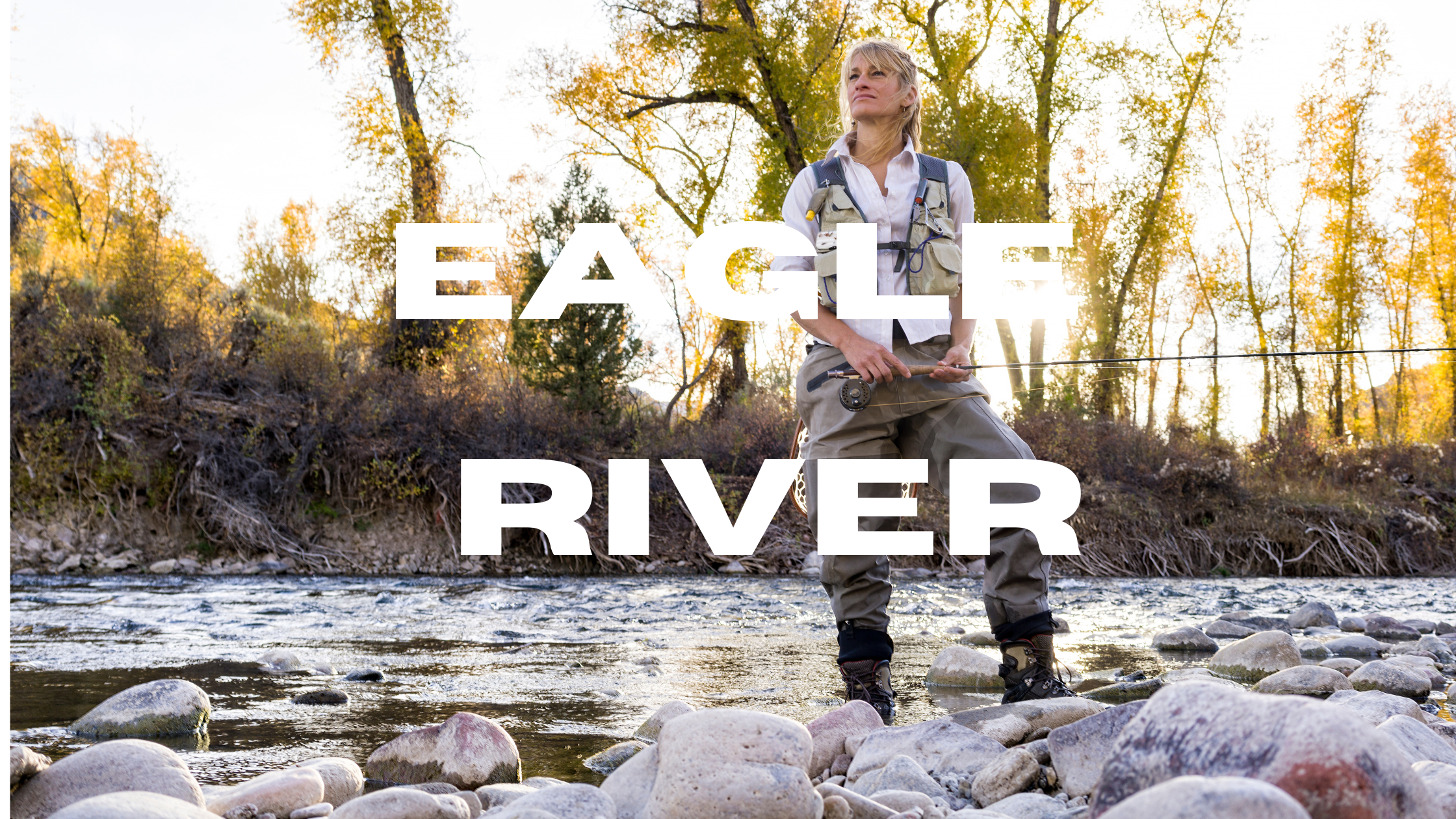 An angler wading in the Slate River near Crested Butte, Colorado, surrounded by autumn colors and casting into the crystal-clear water."