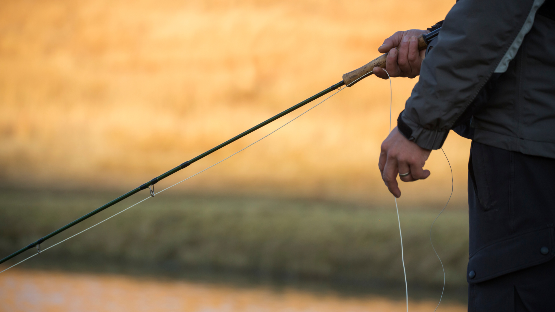 An angler fly fishing in an urban setting in Denver, casting a line into the South Platte River with downtown buildings in the background.